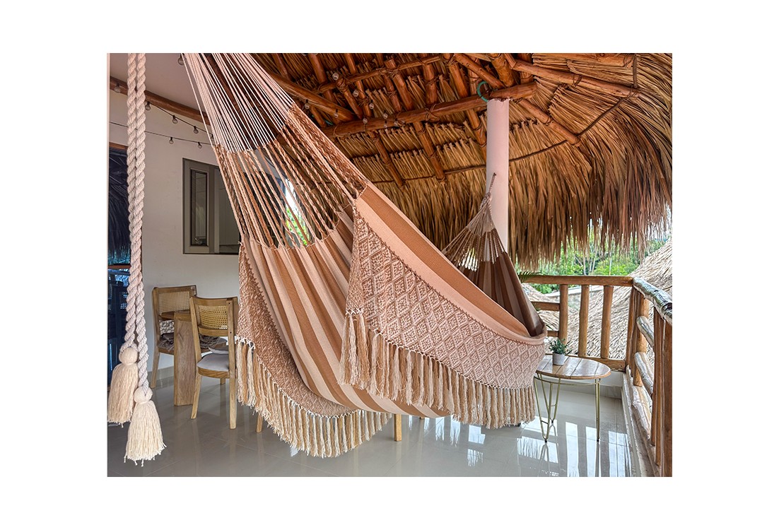 Hamac colombien en coton naturel de couleur beige, taille L, élégamment suspendu dans un environnement extérieur
