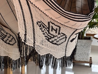 Détail du tissage artisanal du hamac colombien : un motif distinctif sur le bord foncé avec franges, sur fond beige clair