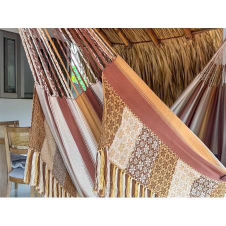 Gros plan des rayures verticales dans les tons terre du hamac colombien, soulignant la robustesse des cordes de fixation