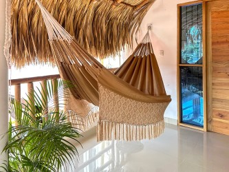 Grand hamac DUNA dans un environnement de terrasse avec plantes, idéal pour le repos en extérieur