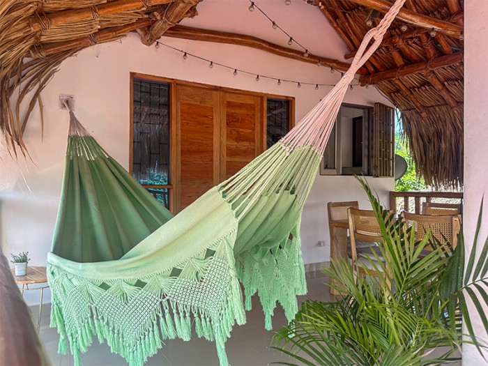 Hamac artisanal macrame colombien vert pastel XXL suspendu sur une terrasse Hamac artisanal macrame colombien vert pastel XXL suspendu sur une terrasse