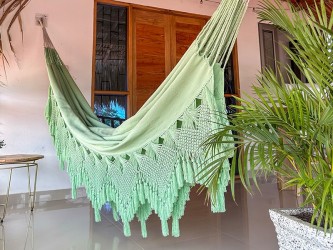 Grand hamac vert pastel suspendu entre deux poteaux en bois