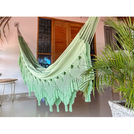 Grand hamac vert pastel suspendu entre deux poteaux en bois