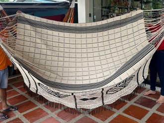 Hamac colombien plié présentant le motif complet de son bord artisanal foncé et la texture de son tissage beige à rayures