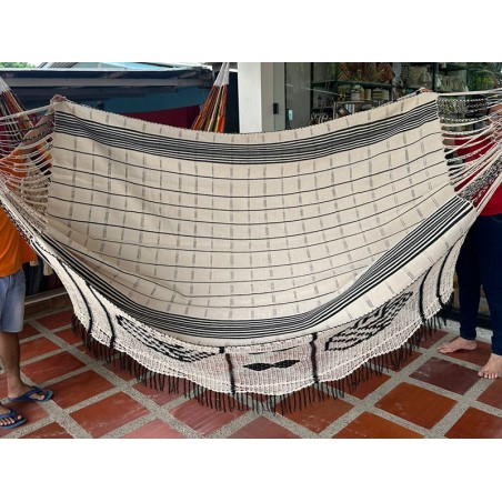 Hamac colombien plié présentant le motif complet de son bord artisanal foncé et la texture de son tissage beige à rayures