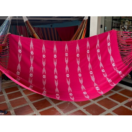 Hamac colombien XL avec son tissu rouge vibrant et le motif brodé distinctif des bords, exposant son design unique et artistique