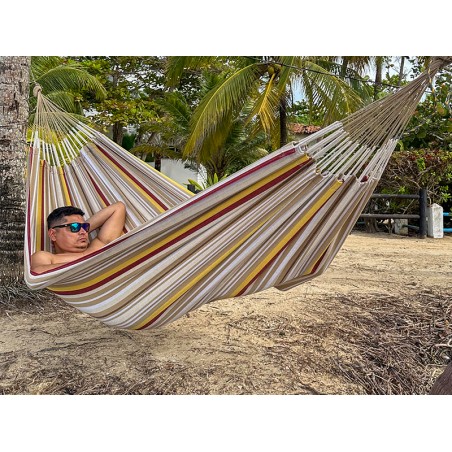 Homme se reposant dans un hamac L en Colombie, aux rayures jaunes, bordeaux et sable. Un modèle sobre et naturel