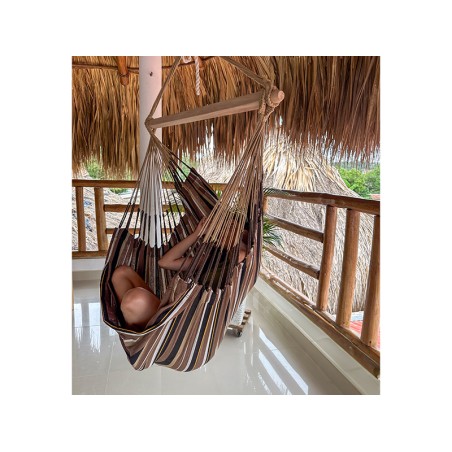 Femme assise confortablement dans une chaise hamac suspendue. Idéale pour la détente en terrasse ou balcon.