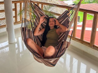 Homme assis confortablement dans une chaise hamac. Design spacieux pour des moments de détente totale.