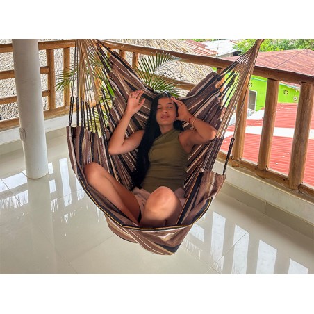 Homme assis confortablement dans une chaise hamac. Design spacieux pour des moments de détente totale.