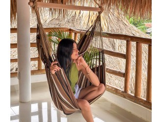 Femme détendue dans une chaise hamac XXL sur une terrasse tropicale