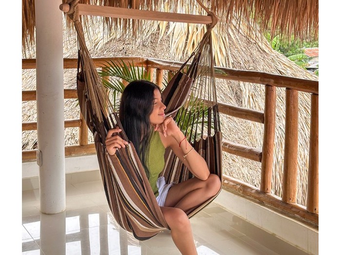 Femme détendue dans une chaise hamac XXL sur une terrasse tropicale