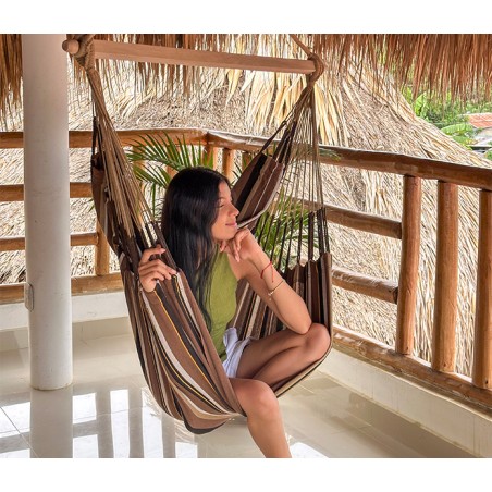 Femme détendue dans une chaise hamac XXL sur une terrasse tropicale