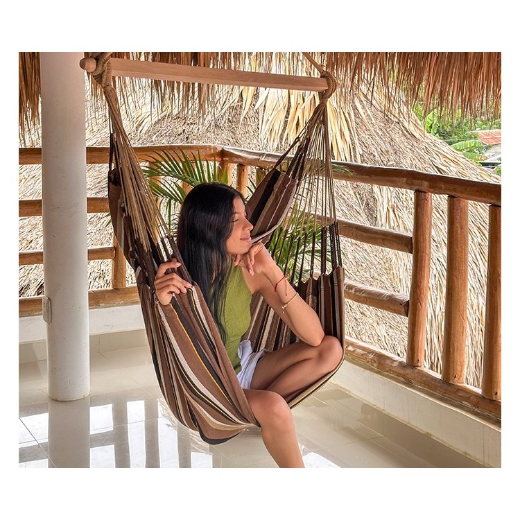 Femme détendue dans une chaise hamac XXL sur une terrasse tropicale