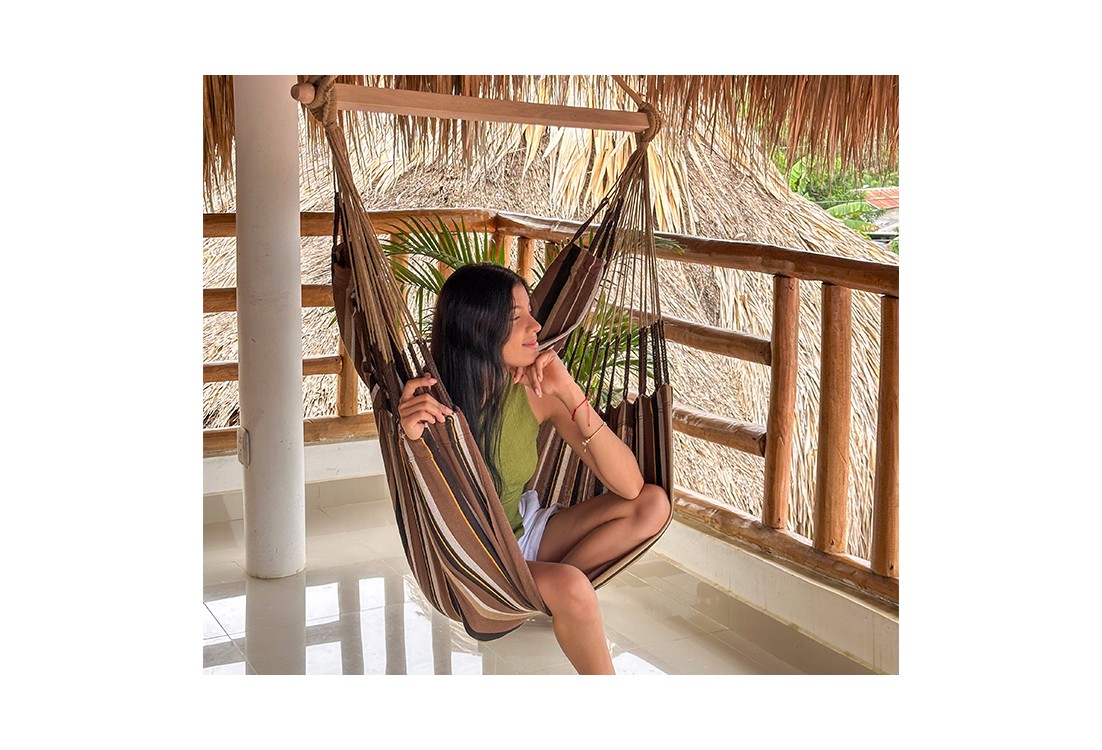 Femme détendue dans une chaise hamac XXL sur une terrasse tropicale