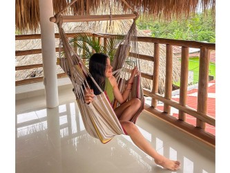 Hamac chaise XL avec femme, sur une terrasse en bois, tons terre