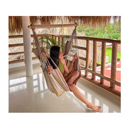 Hamac chaise XL avec femme, sur une terrasse en bois, tons terre