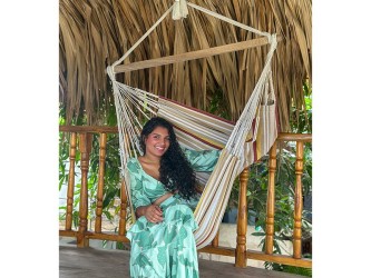 Femme souriante tenant un hamac chaise XXL suspendu, ambiance tropicale