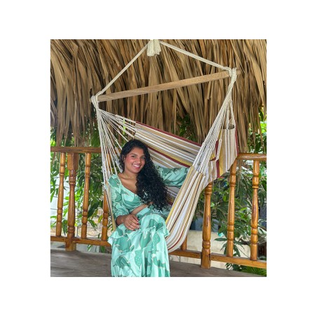 Femme souriante tenant un hamac chaise XXL suspendu, ambiance tropicale