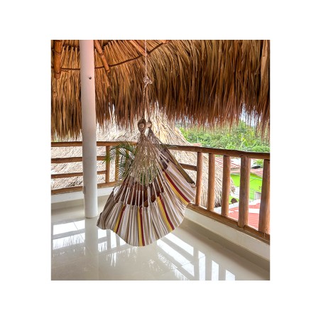 Femme souriante assise dans un hamac chaise XL Elisa en coton recyclé, ambiance chaleureuse