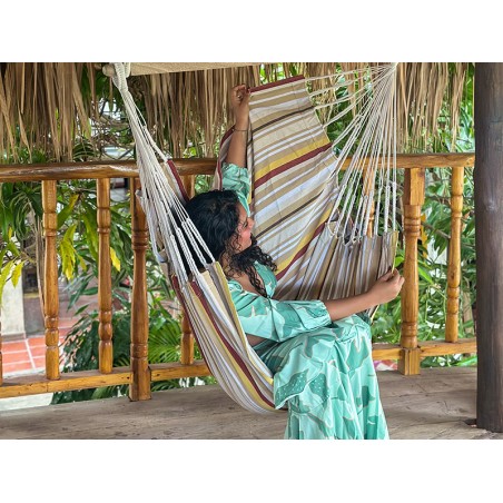 Femme installée dans un hamac chaise XXL en coton recyclé, rayures ocre et beige