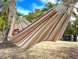 Homme se reposant dans un hamac L en Colombie, aux rayures jaunes, bordeaux et sable. Un modèle sobre et naturel