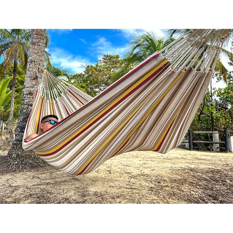Homme se reposant dans un hamac L en Colombie, aux rayures jaunes, bordeaux et sable. Un modèle sobre et naturel
