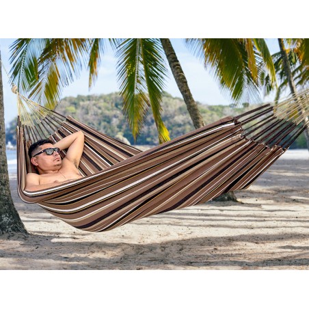 Homme se reposant dans hamac écologique suspendu entre deux cocotiers, sur fond de plage en Colombie