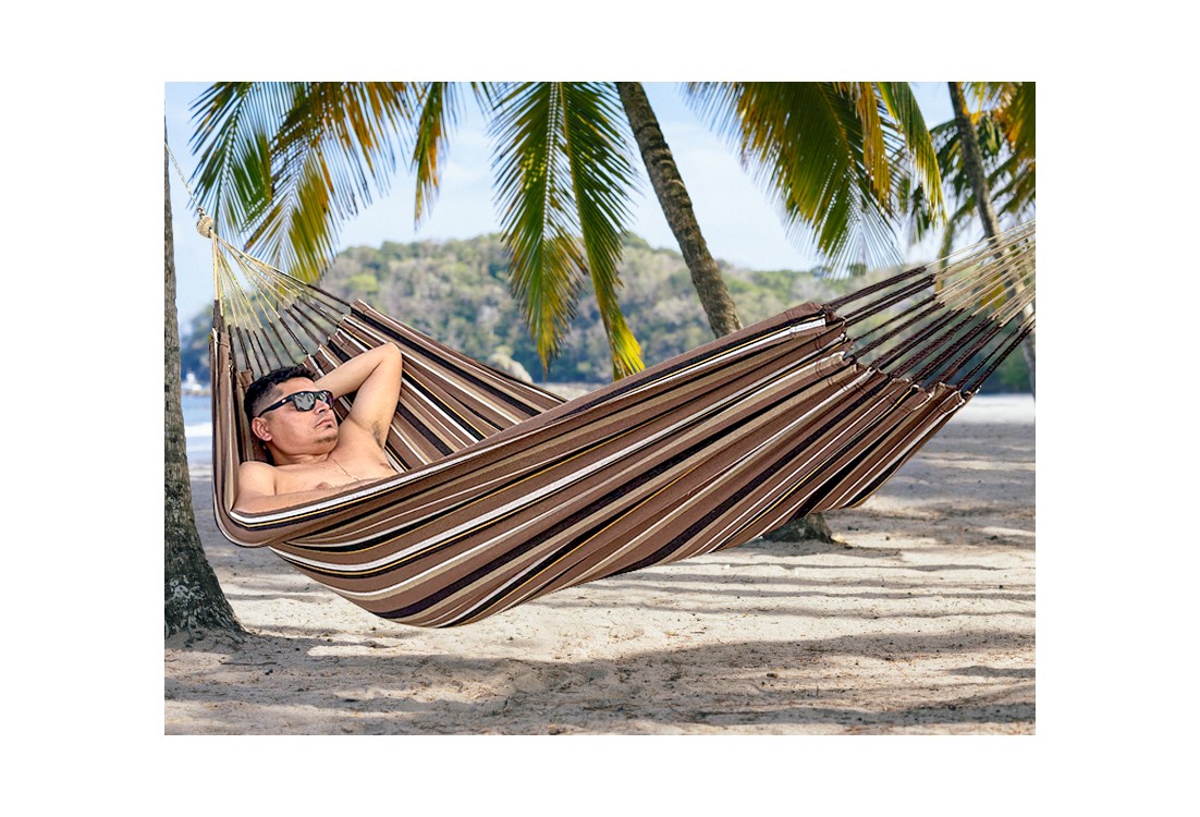 Homme se reposant dans hamac écologique suspendu entre deux cocotiers, sur fond de plage en Colombie