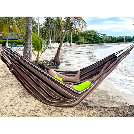 Homme se reposant dans hamac écologique suspendu entre deux cocotiers, sur fond de plage en Colombie