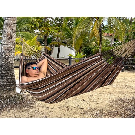 Homme se reposant dans hamac écologique suspendu entre deux cocotiers, sur fond de plage en Colombie