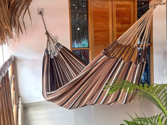 Hamac XXL à rayures marron dominant installé sur une terrasse tropicale