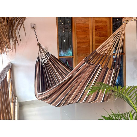Hamac XXL à rayures marron dominant installé sur une terrasse tropicale