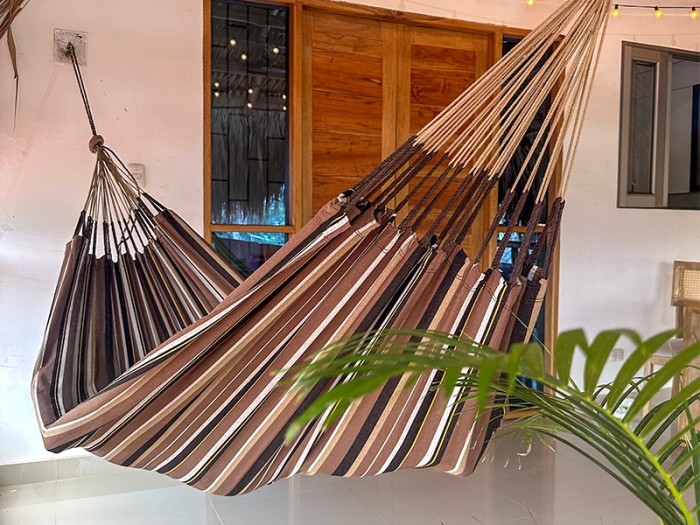 Hamac XXL à rayures marron dominant installé sur une terrasse tropicale