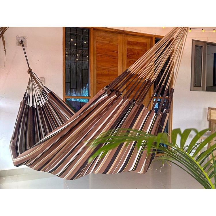 Hamac XXL à rayures marron dominant installé sur une terrasse tropicale