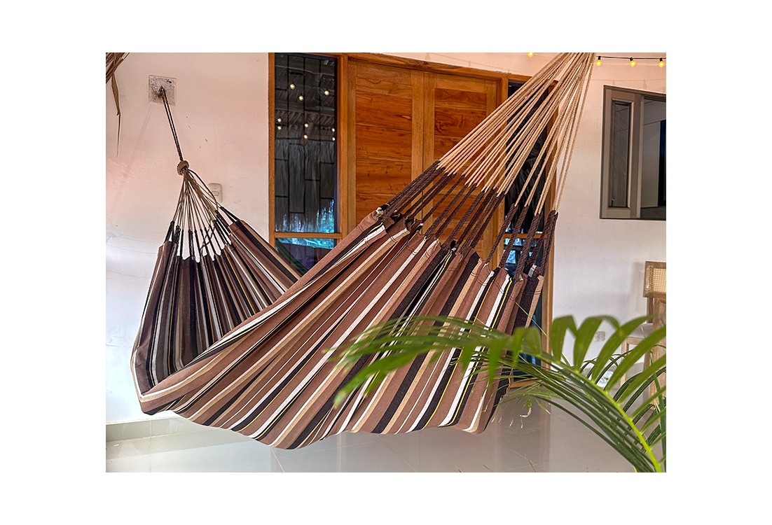 Hamac XXL à rayures marron dominant installé sur une terrasse tropicale