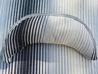 Coussin sur un hamac en tissu à rayures grises et blanches, sur un tissu de texture similaire