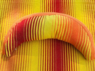 Coussin sur un hamac en tissu à rayures rouges et jaunes, sur un tissu de texture similaire