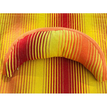 Coussin sur un hamac en tissu à rayures rouges et jaunes, sur un tissu de texture similaire