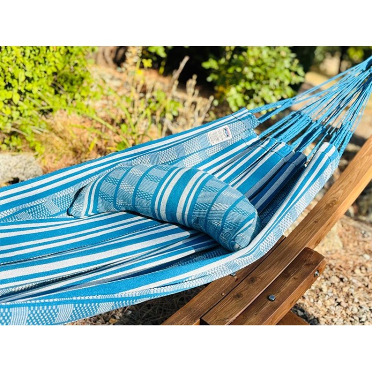 Coussin cervical en tissu polygonal turquoise et blanc, en forme de demi-lune, sur un hamac de même texture
