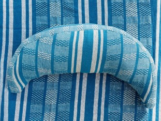 Coussin cervical en tissu polygonal turquoise et blanc, en forme de demi-lune, sur un hamac de même texture