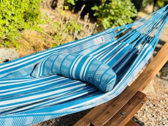 Coussin cervical en tissu polygonal turquoise et blanc, en forme de demi-lune, sur un hamac de même texture