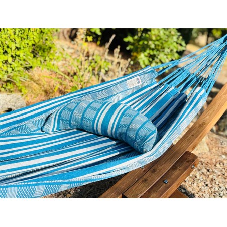 Coussin cervical en tissu polygonal turquoise et blanc, en forme de demi-lune, sur un hamac de même texture