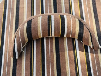 Coussin sur un hamac en tissu à rayures marron et blanches, sur un tissu de texture similaire