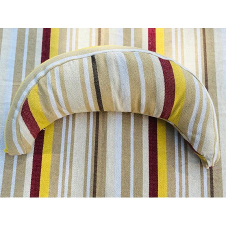 Coussin sur un hamac en tissu à rayures beige, grenat, ocre et blanc, sur un tissu de texture similaire