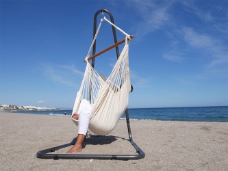 Chaise hamac XXL écru installée sur un support en métal Soledad, avec vue sur la mer, parfaite pour se détendre à l’extérieur