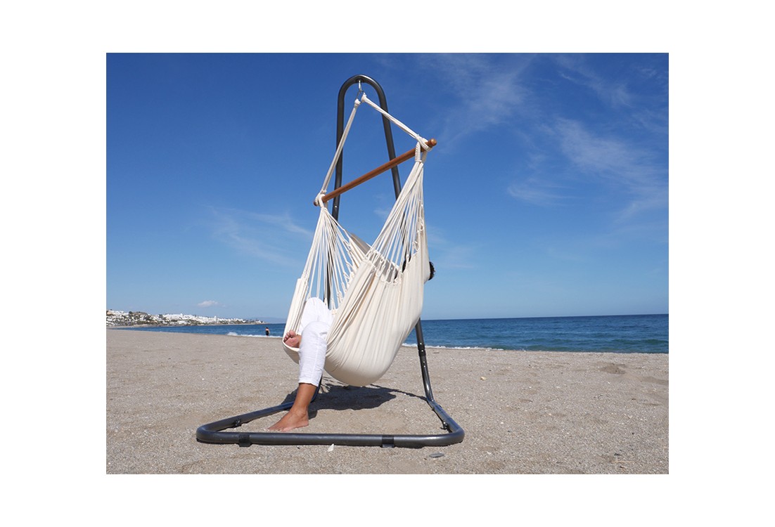 Chaise hamac XXL écru installée sur un support en métal Soledad, avec vue sur la mer, parfaite pour se détendre à l’extérieur