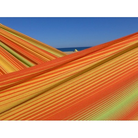 Zoom sur le tissu d’un hamac artisanal aux rayures orange, jaunes et vertes, soulignant la qualité du tissage en coton