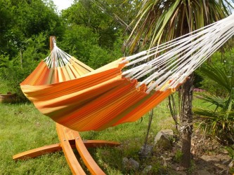 Hamac artisanal colombien suspendu sur un support en bois dans un espace vert