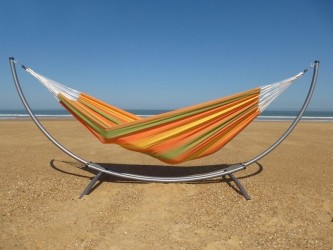 Hamac XXL en toile colorée sur support métallique, installé en extérieur sur le sable